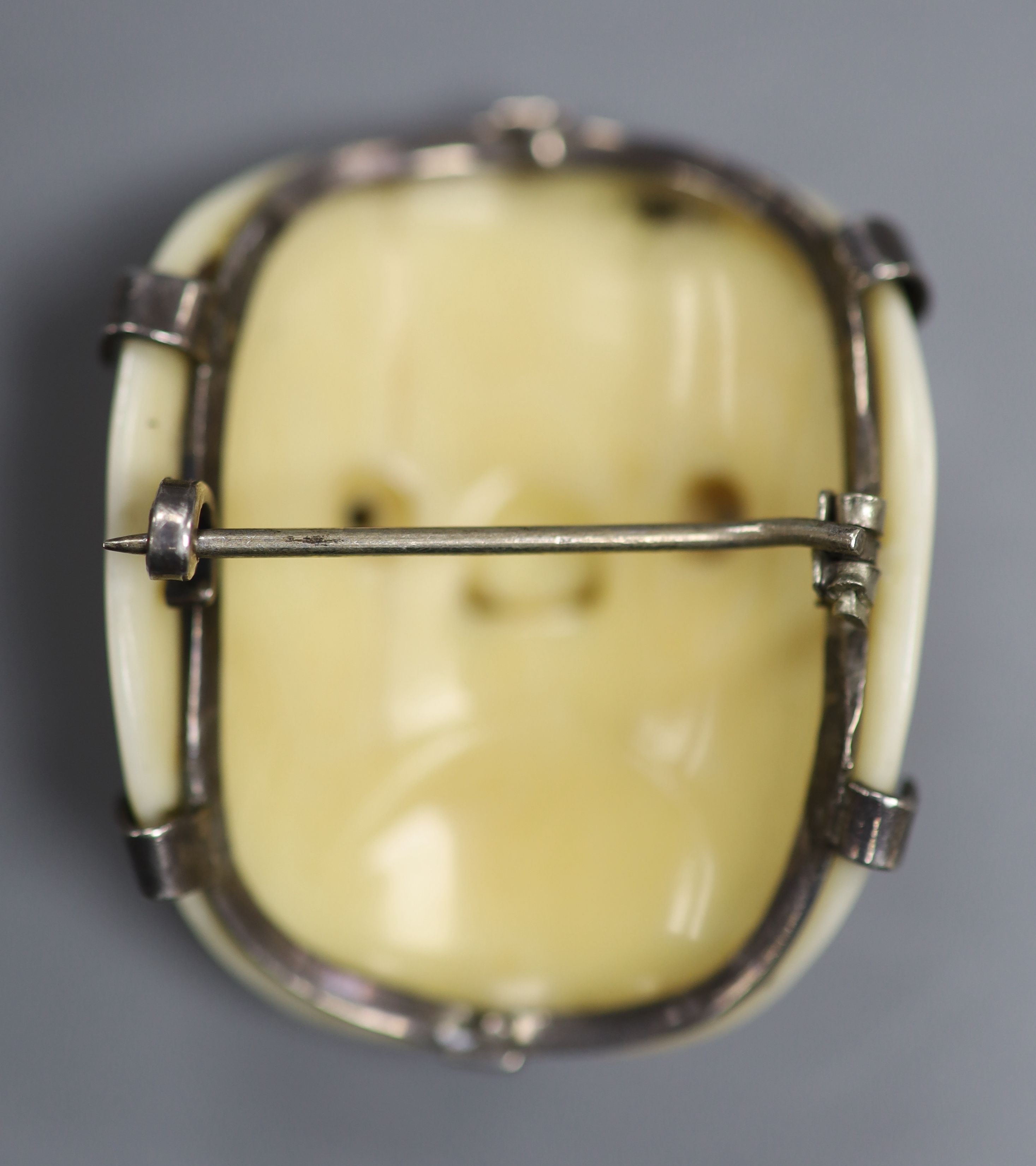 A 19th century Japanese carved ivory Noh mask netsuke mounted as a brooch, 4cm